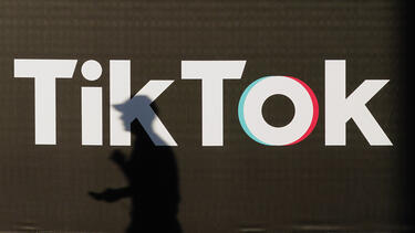 A shadow of a person walking in front of a TikTok sign