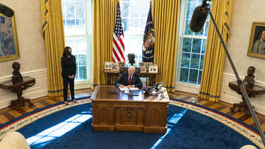 President Joe Biden signing an order at the desk in the Oval Office