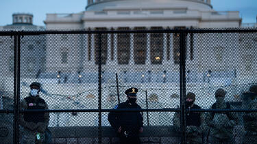 Police and members of the National Guard behind a fence outside the U.S. Capitol on January 7, 2021. 