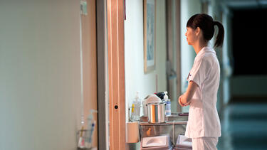 A nurse standing outside a hospital room