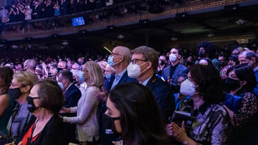Audience members wearing masks in a theater.