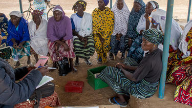 An NGO representative meeting with women in a village in Burkina Faso