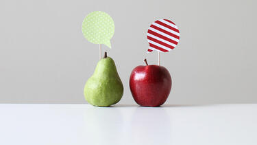 A green pear with a green speech bubble and a red apple with a red speech bubble