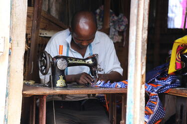 A tailor at work in Freetown, Sierra Leone. Informal settlements are often a hub of commercial activity.