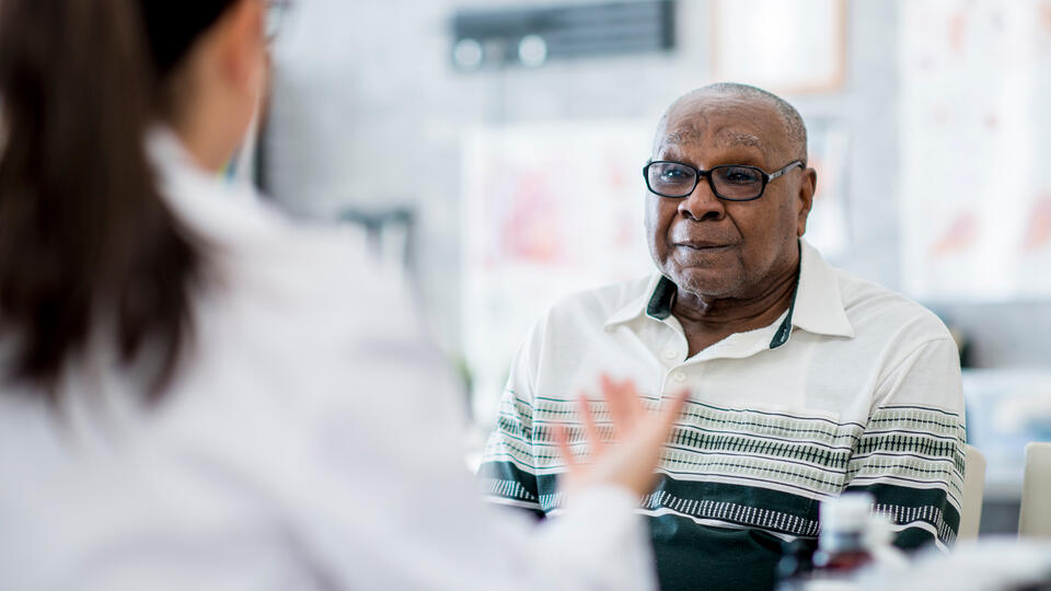 An elderly Black man in conversation with a doctor