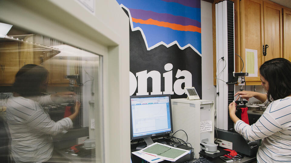A woman using a machine in front of a Patagonia sign, with a reflection in a nearby window