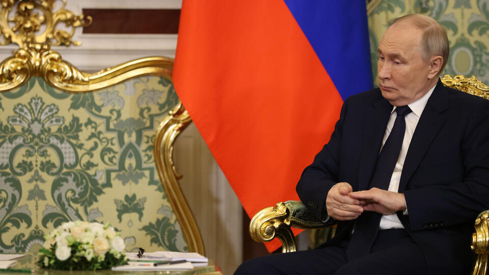 Vladimir Putin sitting alone and grimacing at the Kremlin