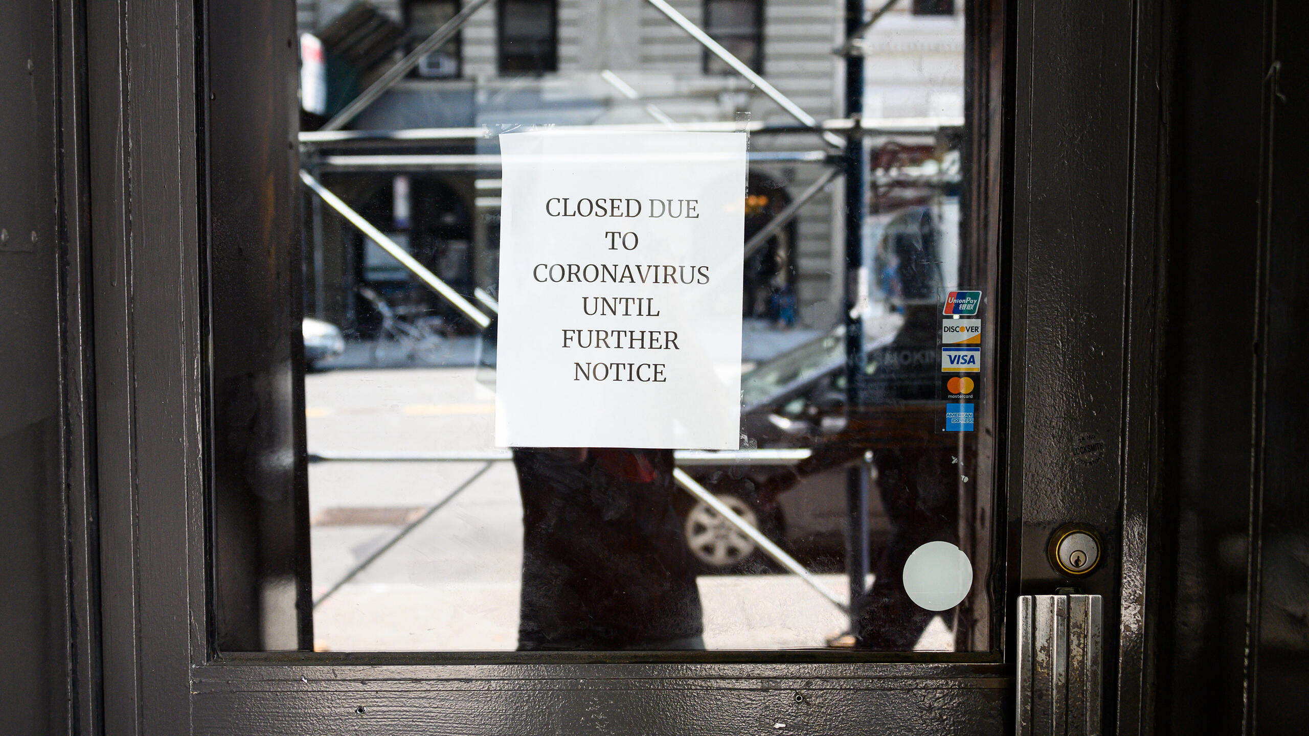 The door to a business with a sign reading "Closed due to cororavirus until further notice"