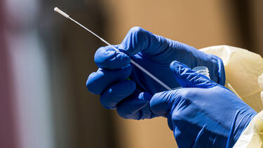 A healthcare worker holding a COVID-19 testing swab