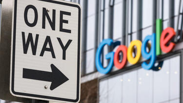 A one way sign next to a Google sign