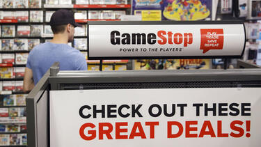 A sign reading "check out these great deals" at a GameStop store