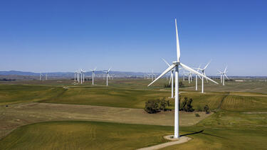A wind farm in Rio Vista, California, with a path winding toward the turbine in the foreground