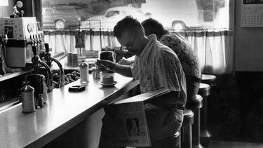 A man reading a newspaper at a diner