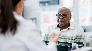 An elderly Black man in conversation with a doctor