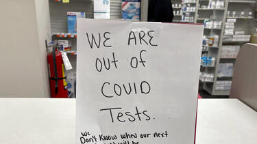 A sign at a drugstore reading "We are out of COVID tests. We don't know when our next shipment will be. We also do not know who does have them."