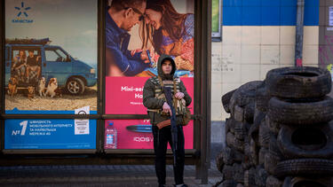 An armed civil defense guard in front of advertisements on a building