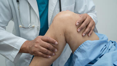 A closeup of a doctor examining a knee