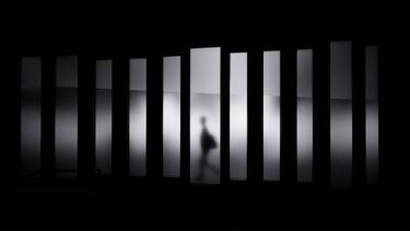 Shadows and a silhouetted figure seen through a series of rectangular openings.