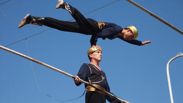 A trapeze artist balancing on the head of another trapeze artist