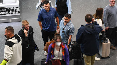 A group of airline passengers, one of whom is wearing a mask.