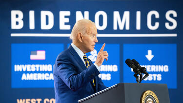 Joe Biden speaking in front of a "Bidenomics" sign