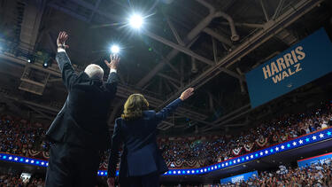 Kamala Harris and Tim Walz from behind at a large rally