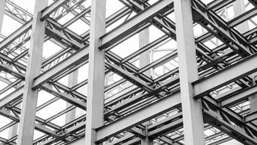 A black and white photo of steel beams in a building under construction