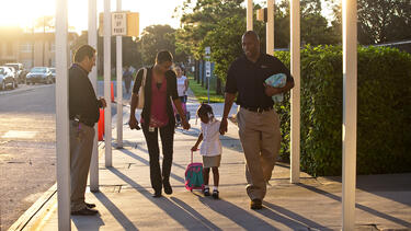 A four-year-old and her parents arriving at school