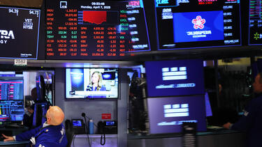 A New York Stock Exchange trader looking at a display showing falling stock prices