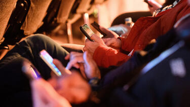 A row of people looking at smartphones