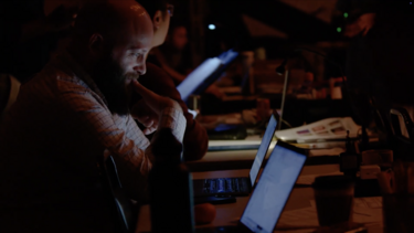 Sam Linden working on a computer in a dark theater
