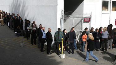 Line of suited workers standing in a queue wrapping around a corner