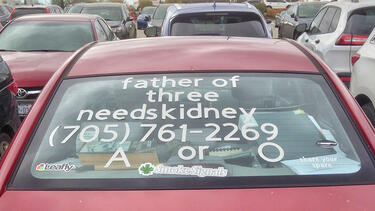 A car with a request for help finding a kidney written on the rear windshield