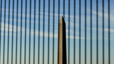 The Washington Monument seen through bars on a window.