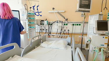 A nurse standing next to a hospital bed and ventilator