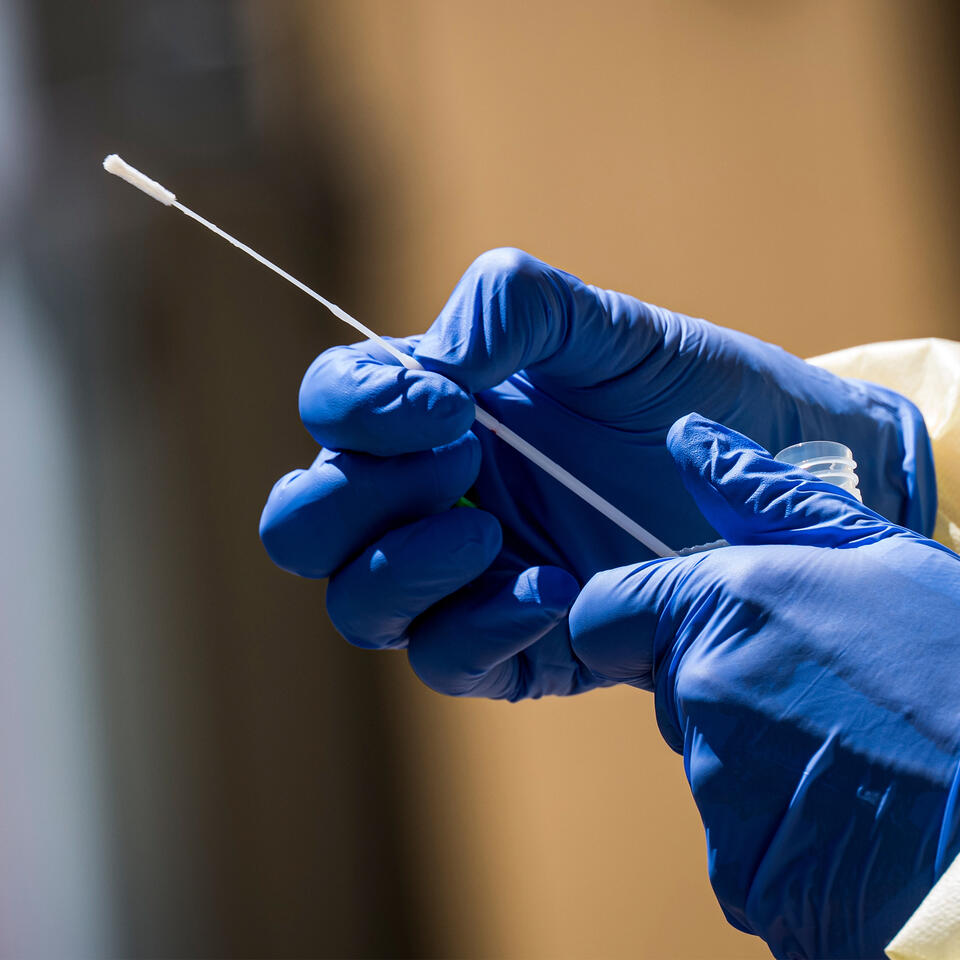 A healthcare worker holding a COVID-19 testing swab