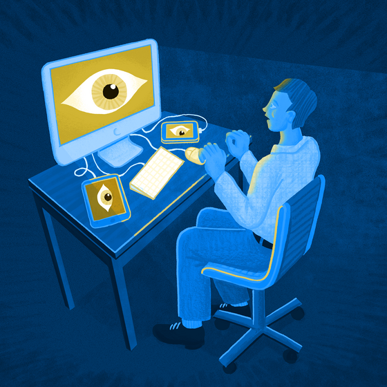A man sitting at a computer, with a large eye on the computer screen, a phone, and a tablet