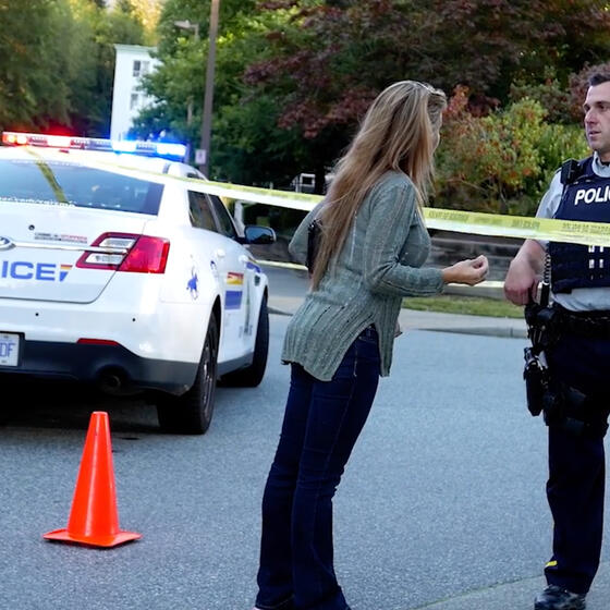 A police officer behind police tape talking to a citizen