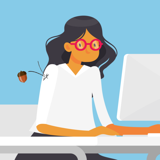 A woman at a desk being nudged by a falling acorn