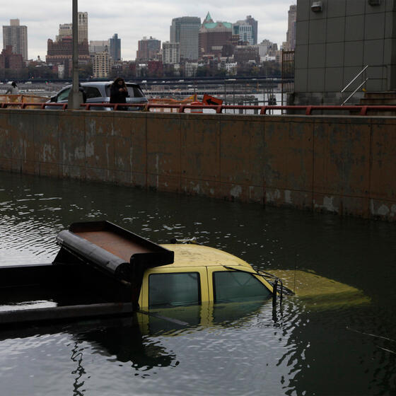 A truck submerged in water with the Manhattan skyline in the background