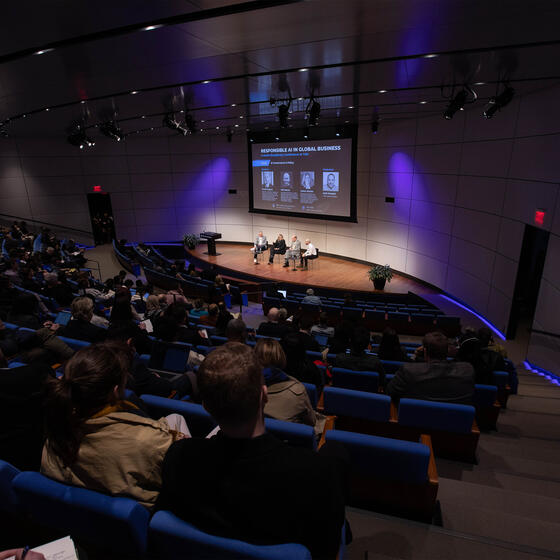 A wide angle of an auditorium with speakers on the stage