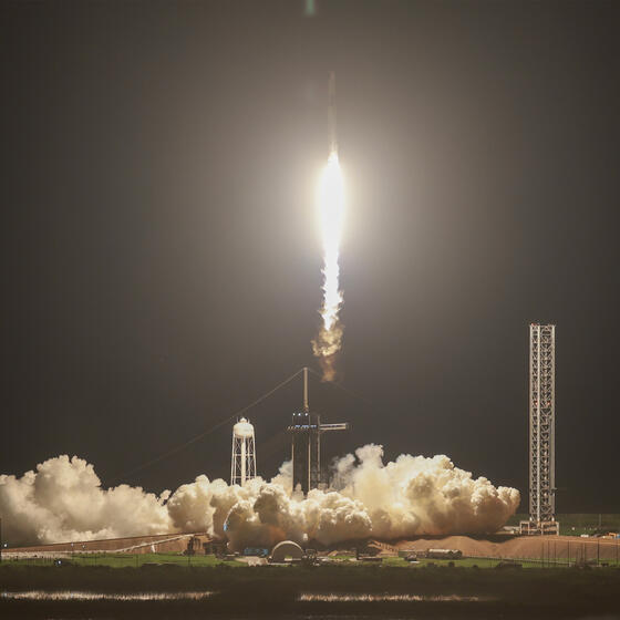 A rocket takes off from a launch pad at night