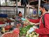 A staff member handing a mask to a vegetable seller in Bangladesh