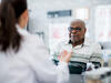 An elderly Black man in conversation with a doctor