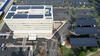 A aerial photo of a 20th-century building retrofitted with solar panels.