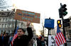 A protester holding a sign reading "unfreeze the federal funds now."